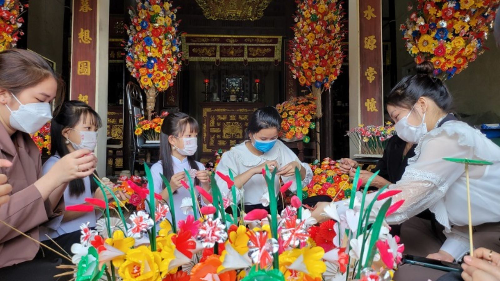 Des visiteurs venus découvrir et s'initier à la confection des fleurs en papier de Thanh Tien.