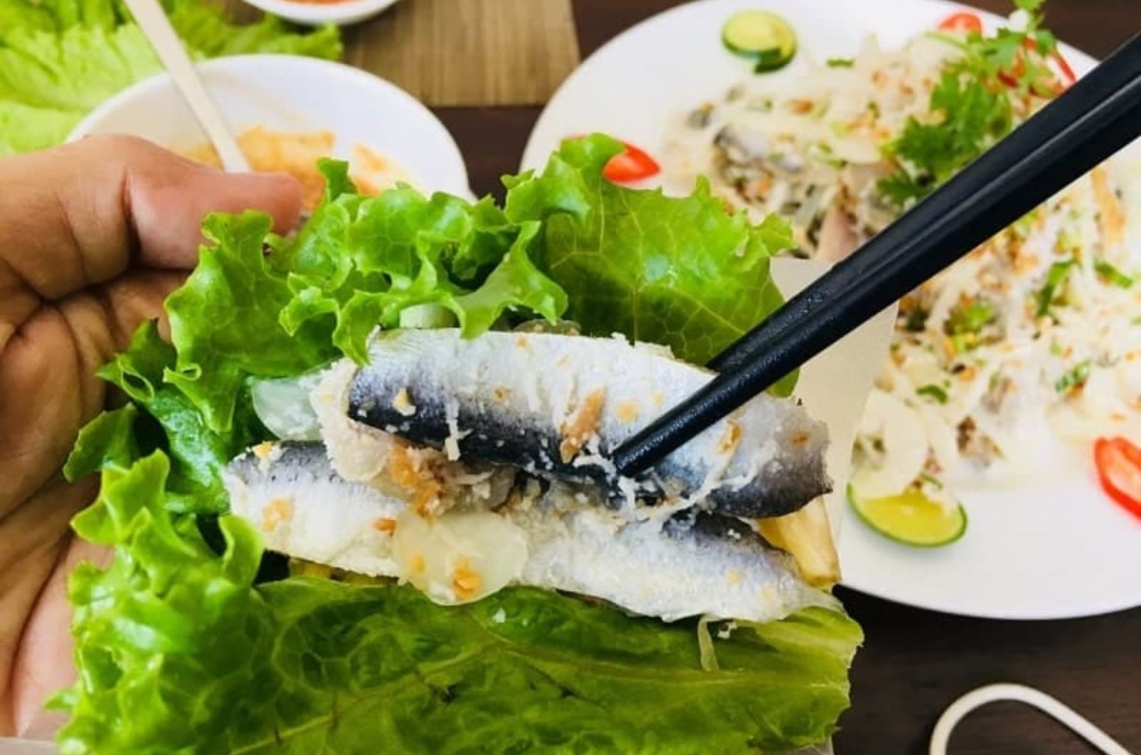 Ăn gỏi cá trích bằng cách cuốn cùng rau